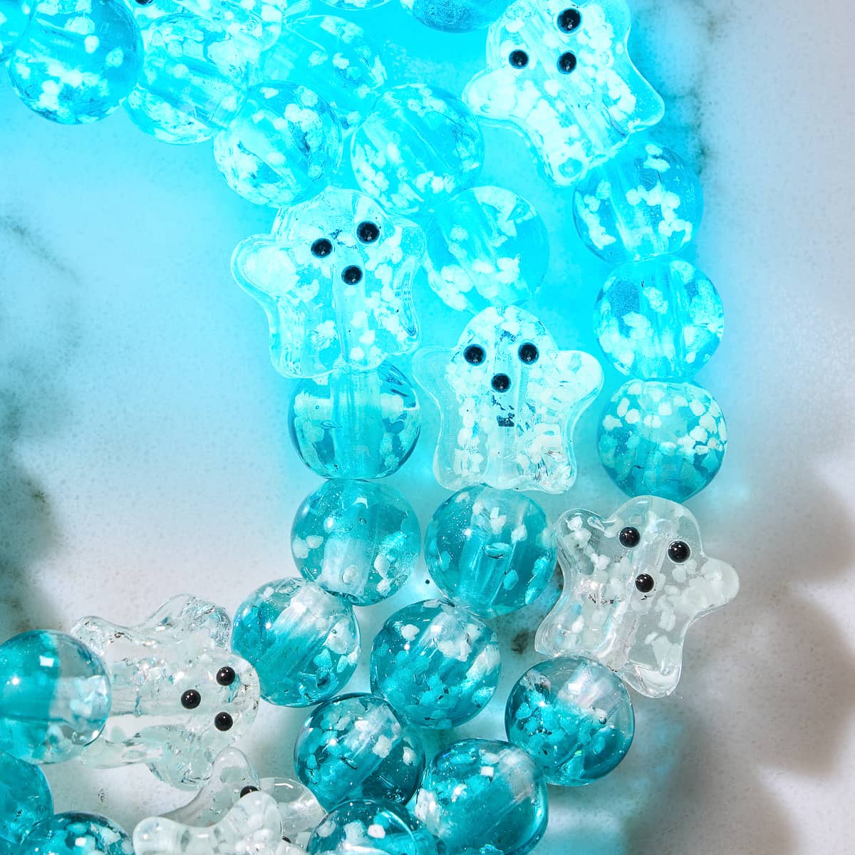 Teal Phantom bracelet close-up of teal and clear Firefly Glass ghost beads with phosphorescent particles on stainless steel base by NOGU
